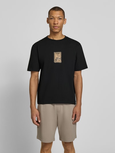 Männermodel trägt Regular Fit T-Shirt aus reiner Baumwolle Modell 'DOBUL' von HUGO in Schwarz, Label Stitching, unifarben, Ganzkörperansicht von vorne