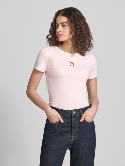 Frauenmodel trägt Slim Fit Damen T-Shirt mit Herz-Stickerei Modell 'ELVA JUNE' von Only in Optik: Unifarben, Rundhals, Kurzarm, Ripp-Material, Ganzkörperansicht von vorne.
