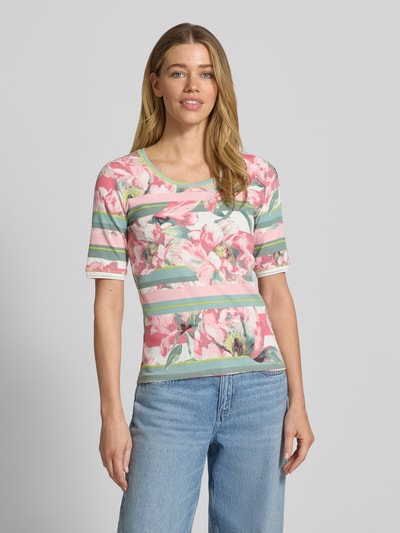 Modelka prezentuje damski t-shirt 'T-Shirt mit floralem Allover-Print' od Betty Barclay, mieszanka bawełny, dopasowany krój, kwiatowy nadruk na całej powierzchni, okrągły dekolt, rękaw o dł. 1/2, długość tyłu w rozmiarze 36: 58 cm, widok całej sylwetki z przodu.