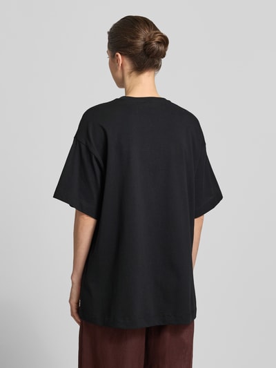 Frauenmodel trägt Oversized T-Shirt aus reiner Baumwolle Modell 'LILIE' von Vero Moda, Optik: Unifarben, Passform: Oversized, Motiv-Print, Ärmelform: Kurzarm, Material: Reine Baumwolle, Ganzkörperansicht Rückansicht.