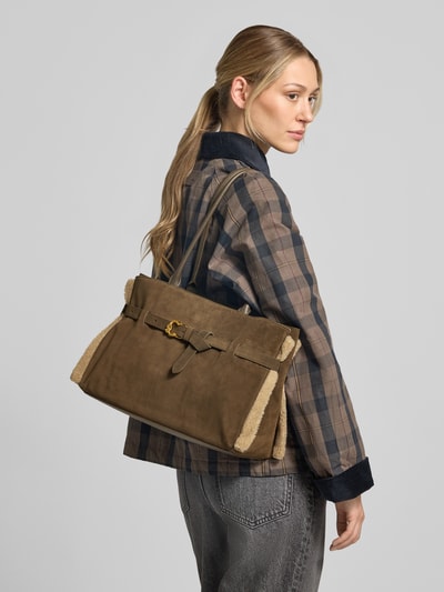 Frauenmodel trägt Handtasche aus echtem Leder Modell 'Sabine' von Coccinelle in Braun, rechteckige Form, Textur mit sichtbaren Nähten, Detailaufnahme Rückansicht. Hauptfach mit Druckknopfverschluss, Schulterriemen, Breite 36 cm, Länge 25 cm, Tiefe 15 cm, Riemenlänge 60 cm.