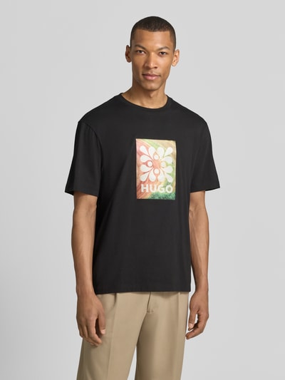 Männermodel trägt Regular Fit T-Shirt aus reine Baumwolle Modell 'DAMORU' von HUGO, schwarz, Foto-Print, Nahaufnahme Oberkörper.