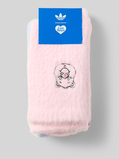 Produktfoto, Care Bear Socken mit elastischem Bund von adidas Originals in flauschigem Rosa mit Care Bear-Motiv und blauer Verpackung