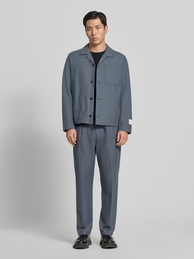 Męski model nosi Oversized Hemdjacke aus Baumwoll-Lyocell-Mix od CK Calvin Klein, niebieska gładka twillowa tkanina, długie rękawy, guziki, kieszenie, widok całej sylwetki z przodu.