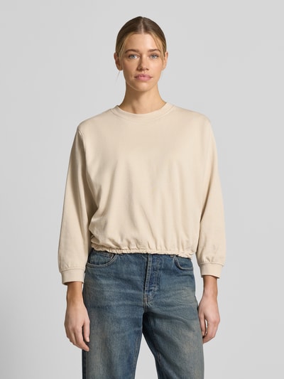 Modelka kobieca ma na sobie beżową bluzę Sweatshirt mit Rundhalsausschnitt Modell 'Saida' od FREE/QUENT z czystej bawełny bio, krój relaxed fit, widok całej sylwetki z przodu.