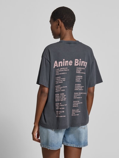 Frauenmodel trägt Relaxed Fit T-Shirt mit Logo-Print von Anine Bing aus reiner Baumwolle in dunklem Grau, Rundhalsausschnitt, kurzärmelig, Rückenlänge bei Größe S 60 cm, Ganzkörperansicht Rückansicht.