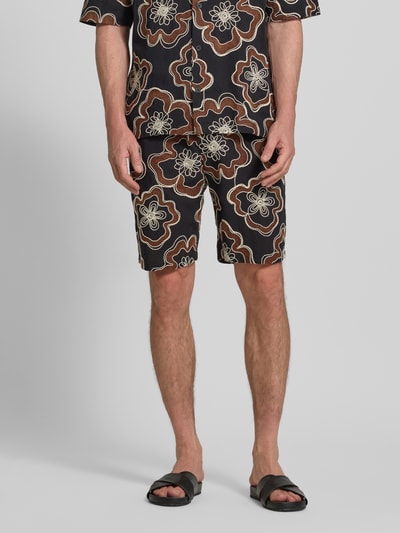 Męski model nosi Straight Fit Shorts mit floralem Allover-Stitching von Antony Morato, czarna bawełna, kwiatowy haft, elastyczny pas ze sznurkiem, kieszeń z tyłu, szerokość w rozmiarze 50: 45 cm, długość nogawki od wewnątrz: 22 cm, widok z przodu na całe ciało.