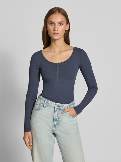 Frauenmodel trägt Slim Fit Langarmshirt aus Baumwoll-Mix Modell 'KITTE' von PIECES in Dunkelblau, Rippstruktur, unifarben, Henley-Ausschnitt, Ganzkörperansicht von vorne.
