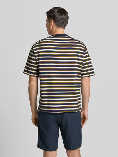 Męski model nosi Relaxed Fit T-Shirt aus reiner Baumwolle Modell 'ASPEN 2' von SELECTED HOMME, granatowo-beżowe paski, tekstura miękka, Ganzkörperansicht Rückansicht.