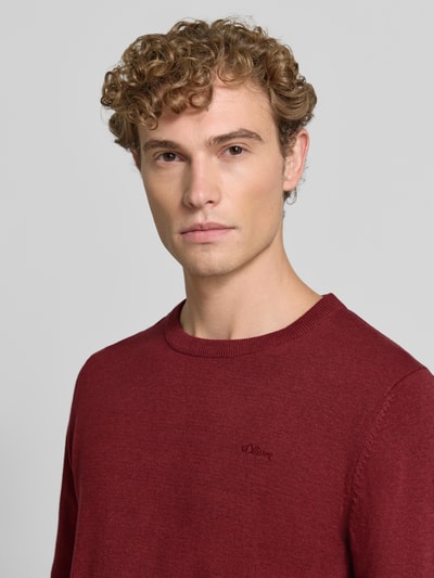 Männermodel trägt Regular Fit Pillover aus reiner Baumwolle von s.Oliver RED LABEL in Dunkelrot, glatte Textur, Nahaufnahme Oberkörper.