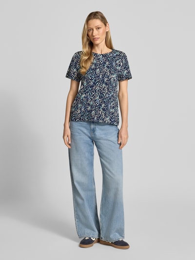 Kobiece modelka nosi Regular Fit T-Shirt aus reiner Baumwolle von Tom Tailor, efekt: wzór w kropki na całej powierzchni, naszywka z logo, okrągły dekolt, krótki rękaw, prosty dół, wykończenie: dżersej, materiał: czysta bawełna, całopostaciowy widok z przodu.