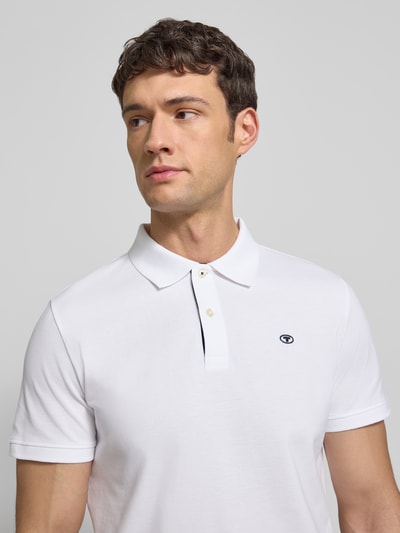 Männermodel trägt Regular Fit Poloshirt mit Logo-Stitching Modell 'BASIC' von Tom Tailor in Optik: Unifarben, Nahaufnahme Oberkörper.