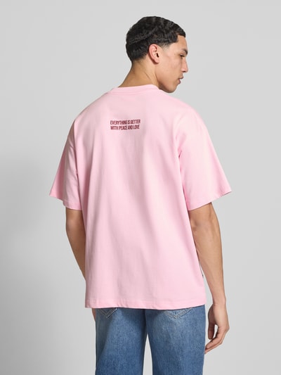 Männermodel trägt Oversized T-Shirt mit Logo-Print von ANOTHER COTTON LAB in Rosa, reine Baumwolle, Rückansicht, Ganzkörperansicht.