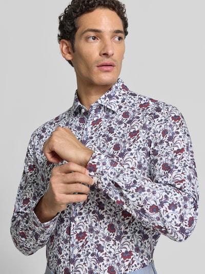 Männermodel trägt Slim Fit Businesshemd aus reiner Baumwolle von Seidensticker, florales Muster in Weiß, Blau und Rot, Nahaufnahme Oberkörper, Herren Businesshemd von Seidensticker.