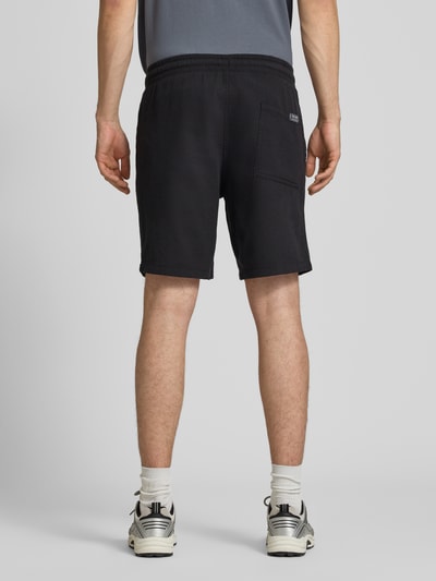 Mannenmodel draagt Shorts met structuurpatroon model 'JAIDEN' van Jack & Jones, puur katoen, regular fit, elastische band, tunnelkoord, kleur zwart, zichtbare achterzak, context: heren korte broek van puur katoen, regular fit, structuurpatroon, elastische band met tunnelkoord, bandwijdte maat M 43 cm, binnenbeenlengte 23 cm, volledige achteraanzicht