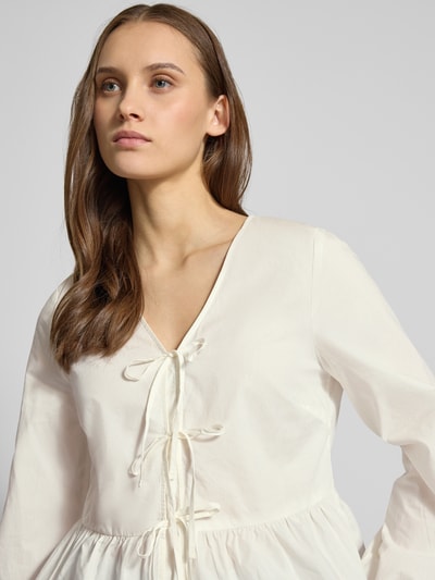 Frauenmodel trägt Slim Fit Langarmbluse aus reiner Baumwolle von Marc O'Polo Denim, unifarben, V-Ausschnitt, Schleifen, Nahaufnahme Oberkörper.