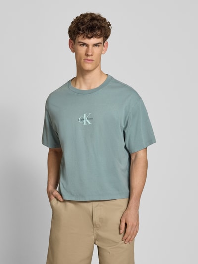 Männermodel trägt Relaxed Fit T-Shirt aus reiner Baumwolle von Calvin Klein Jeans in Optik: Unifarben mit Label-Print, Ganzkörperansicht von vorne.