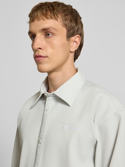 Männermodel trägt Regular Fit Freizeithemd mit Kentkragen und Label-Stitching von Pegador, feines Streifenmuster, Nahaufnahme Oberkörper. Material-Mix mit Stretch, Modell Troy, dezente helle Farbe.