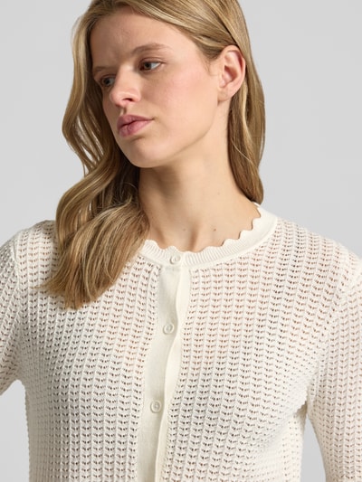 Frauenmodel trägt Regular Fit Strickjacke aus reiner Baumwolle Modell 'SCOUT' von Pieces, Optik: Unifarben, Semitransparente-Optik, einreihige Knopfleiste, Rundhals, Langarm, Rumpfabschluss und Ärmelabschluss gerippt, Materialverarbeitung: Strick, Nahaufnahme Oberkörper.