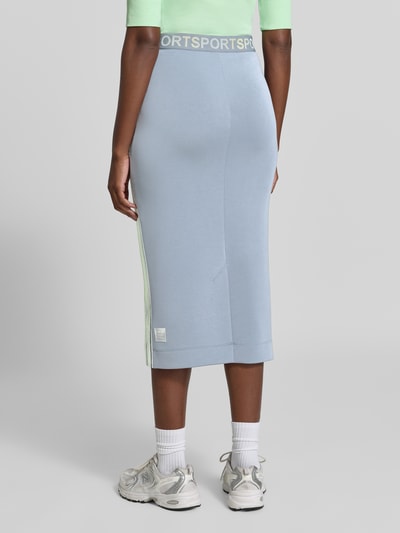 Frauenmodel trägt Midirock aus Lyocell-Mix von Marc Cain, hellblau mit Statement-Print, elastischem Bund, Gerade Passform, Ganzkörperansicht Rückansicht.