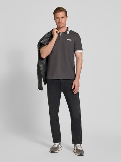 Männermodel trägt Regular Fit Poloshirt aus Baumwoll-Mix von s.Oliver RED LABEL in Optik: Unifarben mit Label-Print, Ganzkörperansicht von vorne.