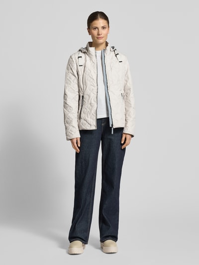 Modelka kobieca nosi Jacke mit Stehkragen und Reißverschlusstaschen od Gil Bret w kolorze jasnym, krój slim fit, czysta bawełna, kaptur z tunelem, tekstura pikowana, długość tyłu w rozmiarze 36: 61 cm, szerokość ramion w rozmiarze 36: 37 cm, szerokość w rozmiarze 36: 50 cm, długość rękawa w rozmiarze 36: 64 cm, widok całej sylwetki z przodu