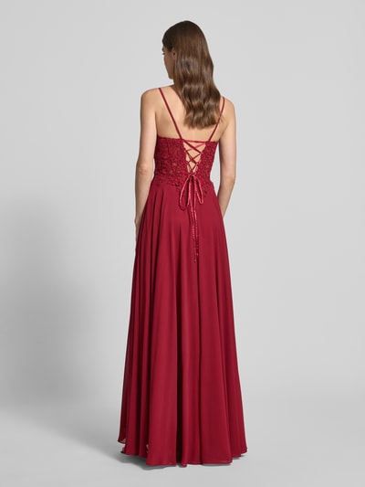Kobiece model prezentuje Abendkleid mit floralem Spitznbesatz od Mascara, głęboka czerwień, koronka z kwiatowym wzorem, połyskujące kamienie, spódnica z szyfonu, widoczny kryty zamek i wiązanie z tyłu, dopasowany krój, szerokość w rozmiarze 36: 40 cm, długość tyłu: 152 cm, widok całej sylwetki z tyłu.