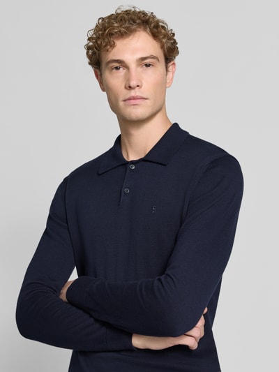 Męskia model nosi Slim Fit Poloshirt aus reiner Baumwolle von armedangels, ciemnogranatowy kolor, jednolita tekstura, zbliżenie na górną część ciała, Herren Poloshirt von armedangels.
