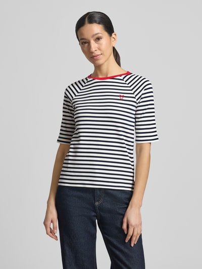 Modelka nosi Shaped Fit T-Shirt aus reiner Baumwolle von Tom Tailor Denim, biało-czarne paski, czerwony haft serca, okrągły dekolt, krótki rękaw, bawełna, widok całej sylwetki z przodu.
