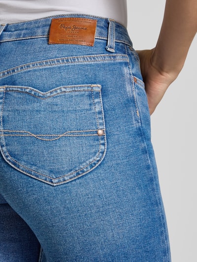Frauenmodel trägt Flared Bootcut-Jeans aus Baumwoll-MIx Modell 'WILLA' von Pepe Jeans in mittlerem Blau, Struktur leicht meliert, Nahaufnahme Rückansicht. Damen Bootcut-Jeans von Pepe Jeans