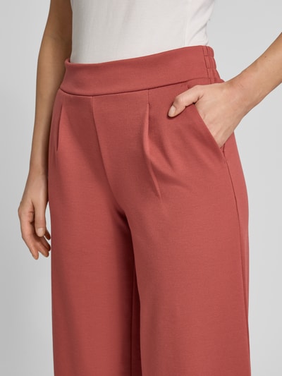 Frauenmodel trägt Wide Fit Stoffhose mit Viskose-Anteil Modell 'Kate' von ICHI in Rot, Bundfalten, Elastischer-Material-Mix, Nahaufnahme Oberkörper.