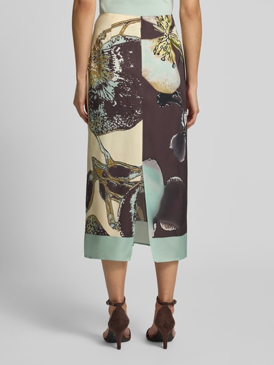 Frauenmodel trägt Midirock aus Viskose im Allover-Look von Marc Cain in Creme, Braun und Mint mit floralen Mustern, Ganzkörperansicht Rückansicht.