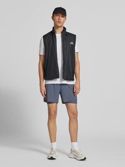 Männermodel trägt Regular Fit Trainingsjacke mit Belüftungsschlitz am Rücken von adidas Training in Schwarz, Ganzkörperansicht von vorne.