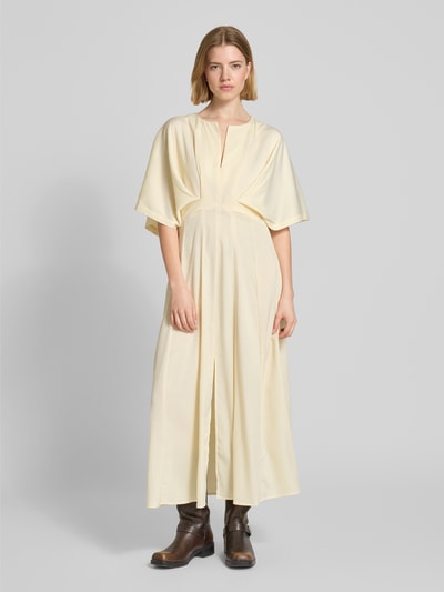 Vrouwenmodel draagt Midikleid met V-hals model 'VIANNA' van Copenhagen Muse in lichtgeel met draperingen, getailleerde fit, geheel lichaamsaanzicht van voren, ruglengte 130 cm, borstbreedte 40 cm, mouwlengte 28 cm.