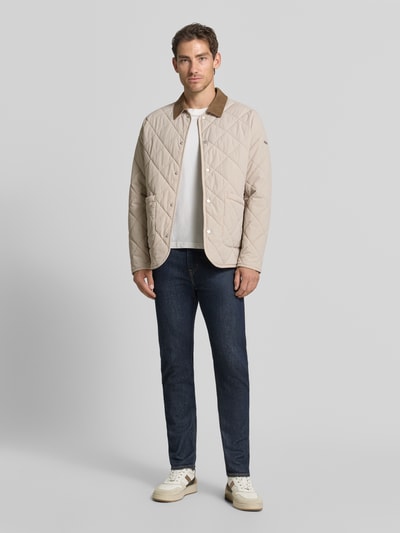 Mannenmodel draagt gewatteerd jack met steekzakken van CINQUE in beige met contrasterende platte kraag, recht pasvorm, doorlopende drukknoopsluiting, ruglengte maat M 76 cm, schouderbreedte 44 cm, borstwijdte 57 cm, mouwlengte 66 cm, elastische materiaalmix, volledig lichaam vooraanzicht.