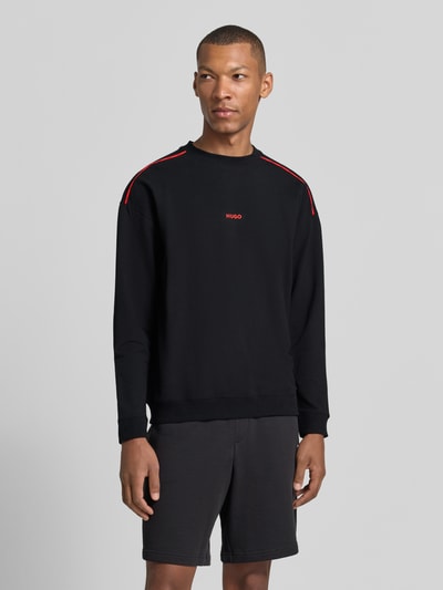 Männermodel trägt Regular Fit Sweatshirt aus Baumwoll-Mix Modell 'NOAH' von HUGO in Schwarz mit roten Akzenten, Ganzkörperansicht von vorne, Herren T-Shirt von HUGO