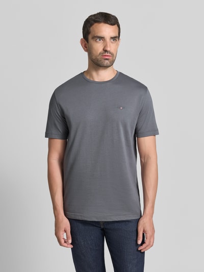 Männermodel trägt Regular Fit T-Shirt aus reiner Baumwolle von GANT in Dunkelgrau, glatte Textur, dezentes Logo, Ganzkörperansicht von vorne.