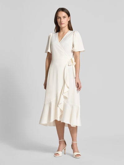 Modelka nosi Regular Fit Midikleid in Wickel-Optik Modell 'Thea' od YAS, kremowa tkanina, falbany, długość do łydki, krótki rękaw, widok całej sylwetki z przodu. Szerokość w rozmiarze 36: 45 cm, długość tyłu 120 cm, długość rękawa 28 cm, elastyczna mieszanka materiałów.