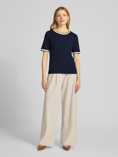 Modelka nosi T-Shirt mit Rundhalsausschnitt und Wellensaum von More & More z bawełny z domieszką elastanu, krój regular fit, granatowy z kontrastowym brzegiem, długość tyłu w rozmiarze 36: 57 cm, pełny widok z przodu.