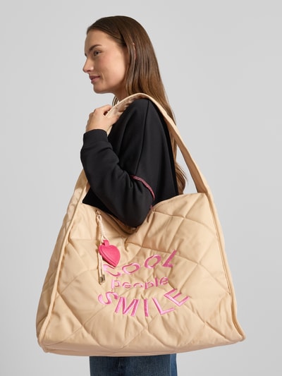Kobiece modelka nosi beżową 'Handtasche mit Statement-Stitching' od miss goodlife z pikowaną strukturą i różowym napisem, główna komora na zamek, kieszeń wewnętrzna na zamek, szerokość w rozmiarze 1: 46 cm, długość 38 cm, głębokość 20 cm, długość paska na ramię 75 cm, widok na cały korpus z przodu.