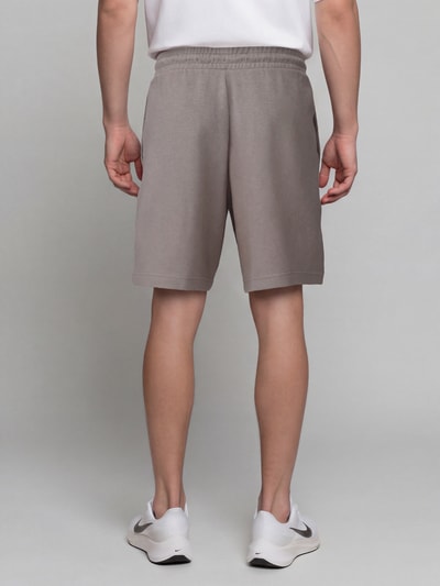Männermodel trägt Relaxed Fit Sweatshorts aus Baumwoll-Mix 'ESS ELEVATED' von PUMA in Hellbraun, glatte Textur, Ganzkörperansicht Rückansicht, Herren Sweatshorts von PUMA Performance.
