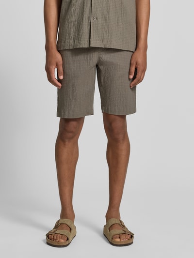 Männermodel trägt Shorts mit elastischem Bund und Strukturmuster von Lindbergh, Baumwoll-Mix mit Stretch-Anteil, Loose-Fit, Seitliche Eingrifftaschen, Bundweite 42 cm, Innenbeinlänge 25 cm, Ganzkörperansicht von vorne.