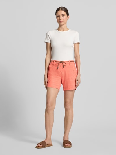 Frauenmodel trägt Bermudas mit Bindegürtel und Eingrifftaschen von G.I.G.A. DX in Koralle, Baumwoll-Mix mit Stretch-Anteil, Ganzkörperansicht von vorne.