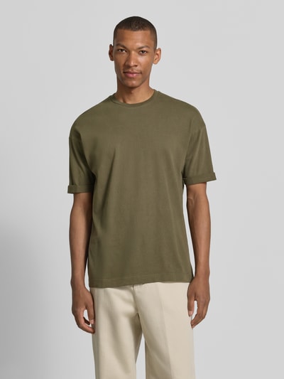 Männermodel trägt T-Shirt mit Ärmelaufschlag und Rundhalsausschnitt von Drykorn aus Reine Baumwolle, Regular-Fit, oliv, Ganzkörperansicht von vorne. Rückenlänge bei Größe M: 70 cm, Ärmel mit Aufschlag.