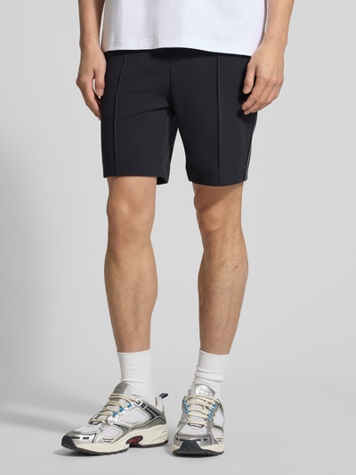 Männermodel trägt Regular Fit Shorts aus Baumwoll-Mix Modell 'T_JOIN Headlo' von BOSS Green in Unifarben, Kontraststreifen, Nahaufnahme Unterkörper.