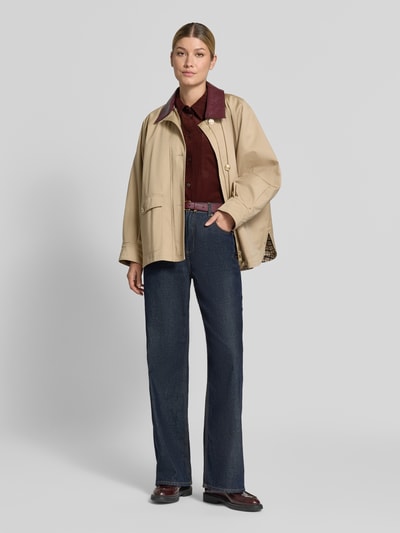 Frauenmodel trägt Regular Fit Langarmbluse aus reiner Baumwolle Modell 'Fronna' von OPUS in dunklem Rot, kombiniert mit Jeans und beigem Mantel, Ganzkörperansicht von vorne.