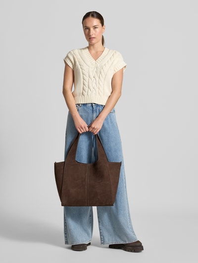 Frauenmodel trägt Tote Bag aus Leder-Mix Modell 'Ramona' von MANGO, breite Form, braune Farbe, sichtbare strukturierte Oberfläche, Ganzkörperansicht von vorne. Breite 54 cm, Länge 33 cm, Tiefe 14 cm, Schulterriemen 62 cm, Hauptfach mit Magnetverschluss.