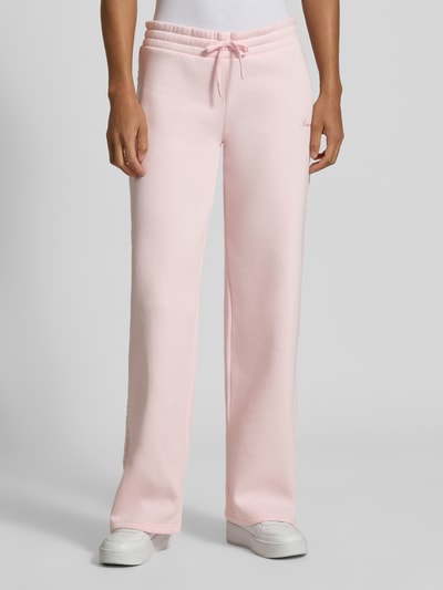 Frauenmodel trägt Wide Fit Sweatpants aus Baumwoll-Mix von REVIEW in Rosa mit elastischem Bund, Bordüre, Label-Stitching, Nahaufnahme Unterkörper.