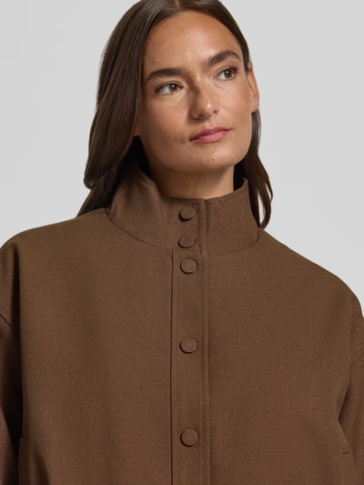 Kobiece model prezentuje Jacke mit Stehkragen Modell 'DATING' od SUNCOO PARIS, brązowy materiał z domieszką wiskozy, krój regular fit, zapięcie na guziki, szerokość w rozmiarze S: 42 cm, długość tyłu: 56 cm, szerokość w klatce piersiowej: 61 cm, długość rękawa: 55 cm, zbliżenie na górną część ciała