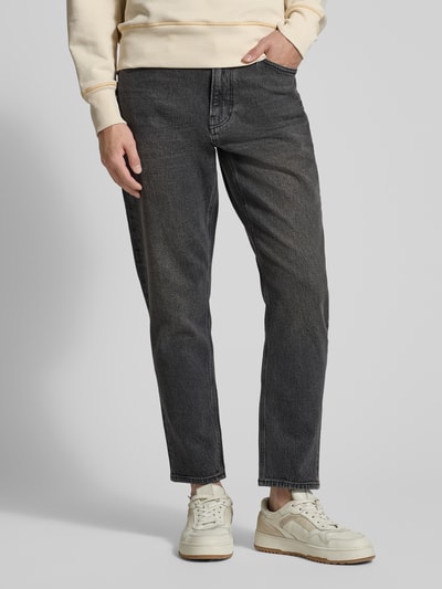 Männermodel trägt Tapered-Fit Jeans aus Bio-Baumwoll-Mix Modell 'MAAKX' von Armedangels, Denim-Optik, 5-Pocket-Design, Ganzkörperansicht von vorne.